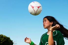 A young person about to hit a soccer ball with their head.