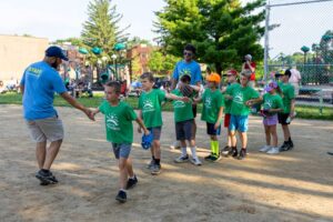 picture of children on a baseball field doing a high five