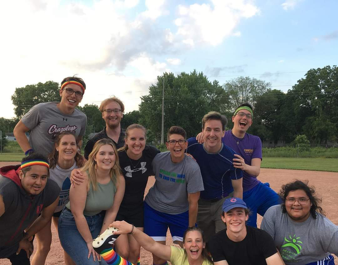 A group of people posing together on a kickball field