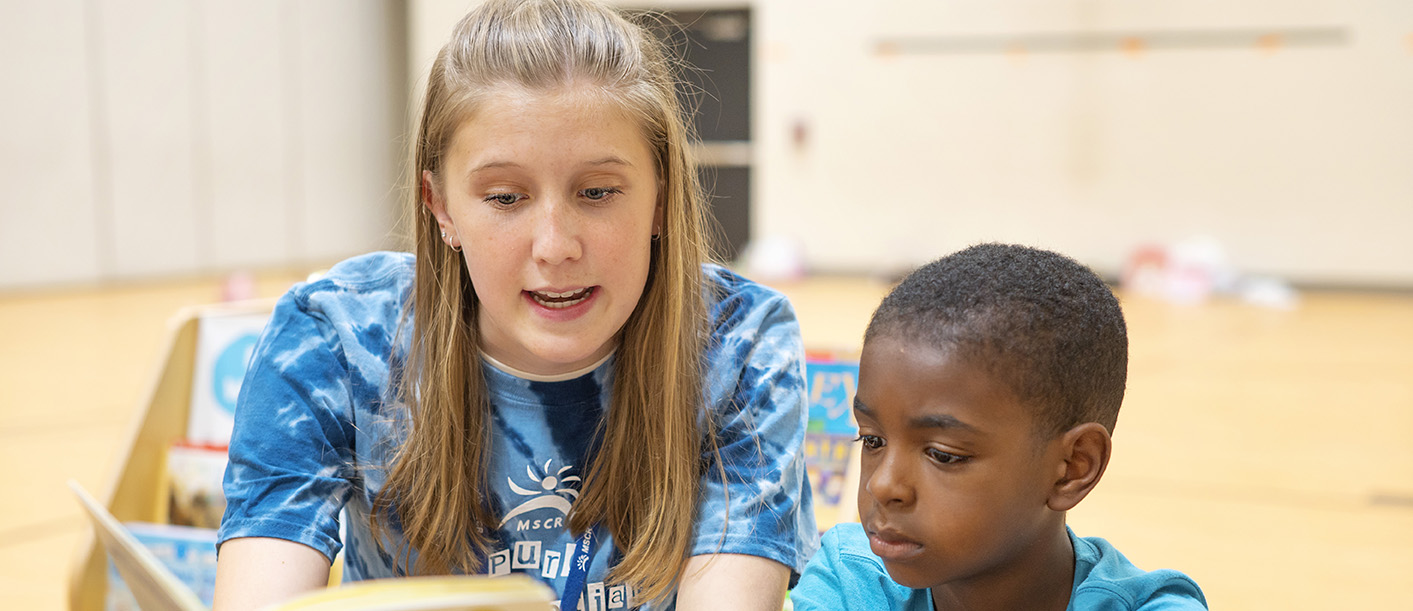 A teen reading to a small boy