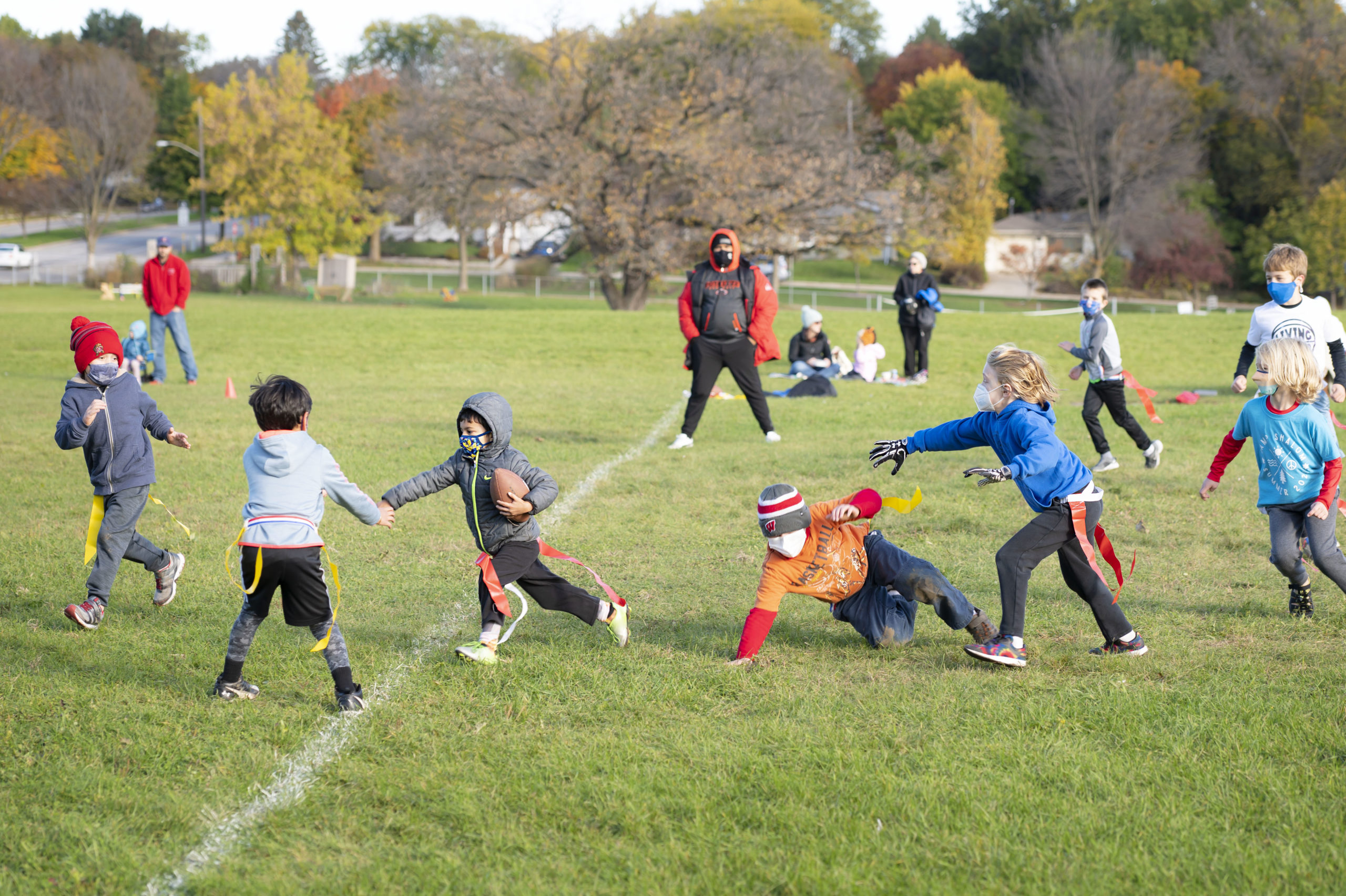 A group of young kids playing football on a field in early fall