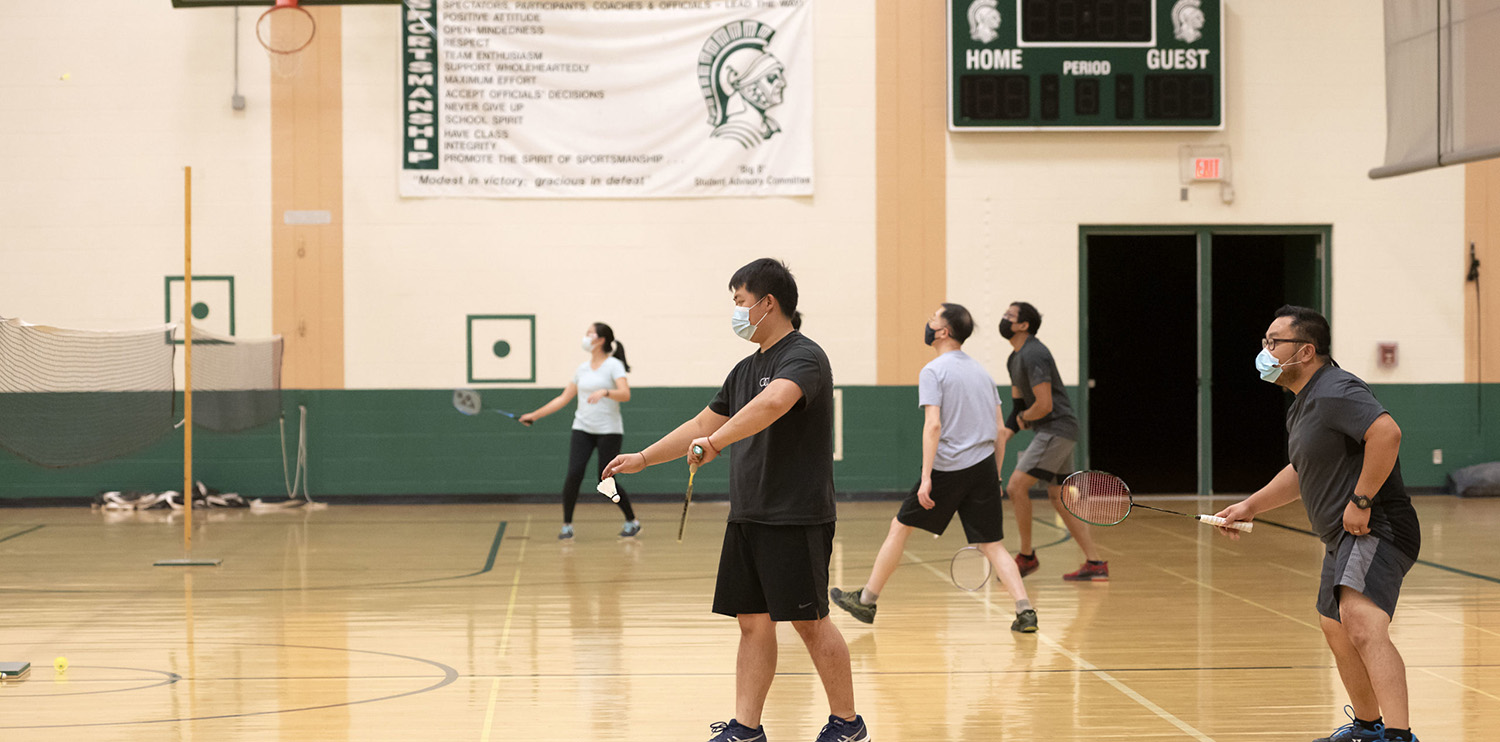 Several groups of people playing badminton in a gymnasium