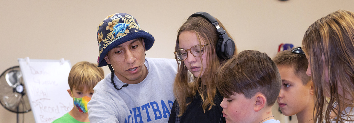 A person showing a group of kids a DJ setup