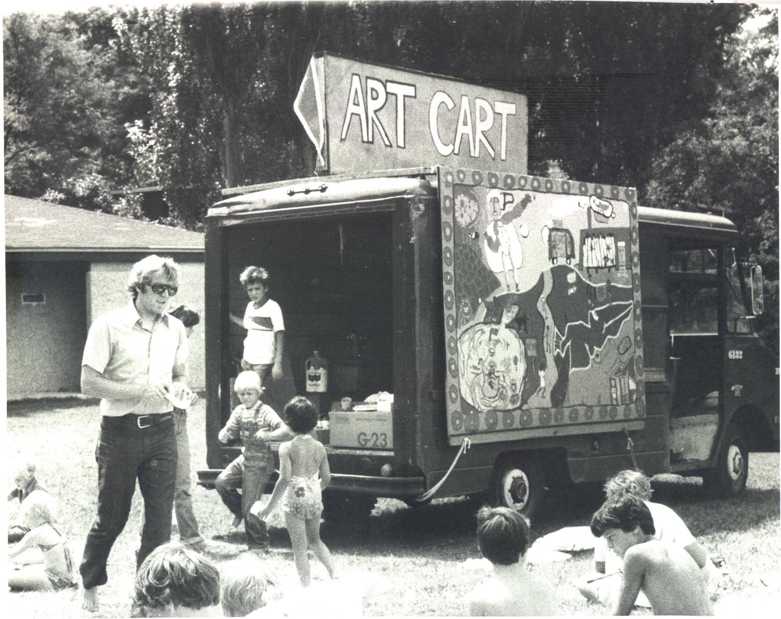 Children playing with art outside in front of a mobile vehicle